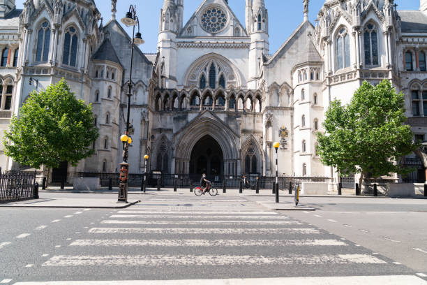 geschlossene royal courts of justice in london wegen coronavirus covid-19 mit einem radfahrer vor neiner gesichtsmaske - royal courts of justice stock-fotos und bilder