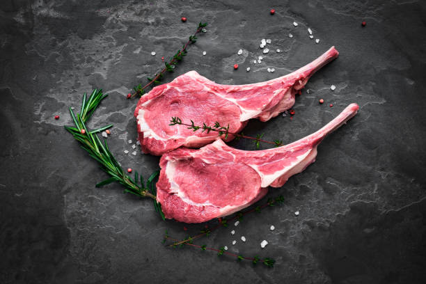 prepared for cooking raw steak of veal on the bone on the dark stone with rosemary and thyme