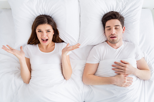 High angle above view photo of crazy lady snoring husband guy couple, lying sheets bed covered blanket unpleasant awakening can't sleep yelling suffer wear pajama room indoors
