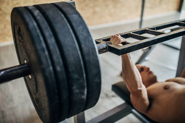 istock Man body builder exercising bench press in gym 1241854246