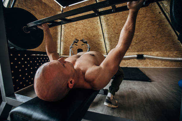 istock Strong man exercising bench press in gym 1241857556