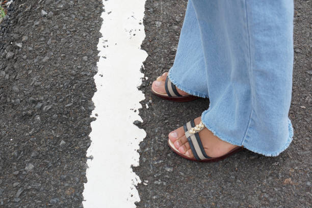 istock woman's foot stands behind a white line on the road. 1241861947