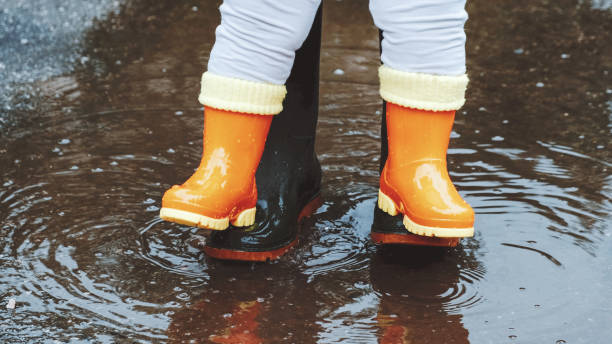 istock Green rubber boots in a puddle after rain. Autumn day. 1241868902