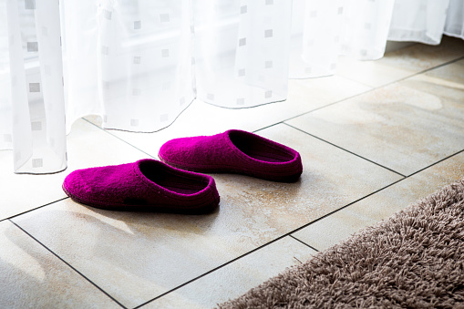 close-up of purple slippers on the floor by a white curtain