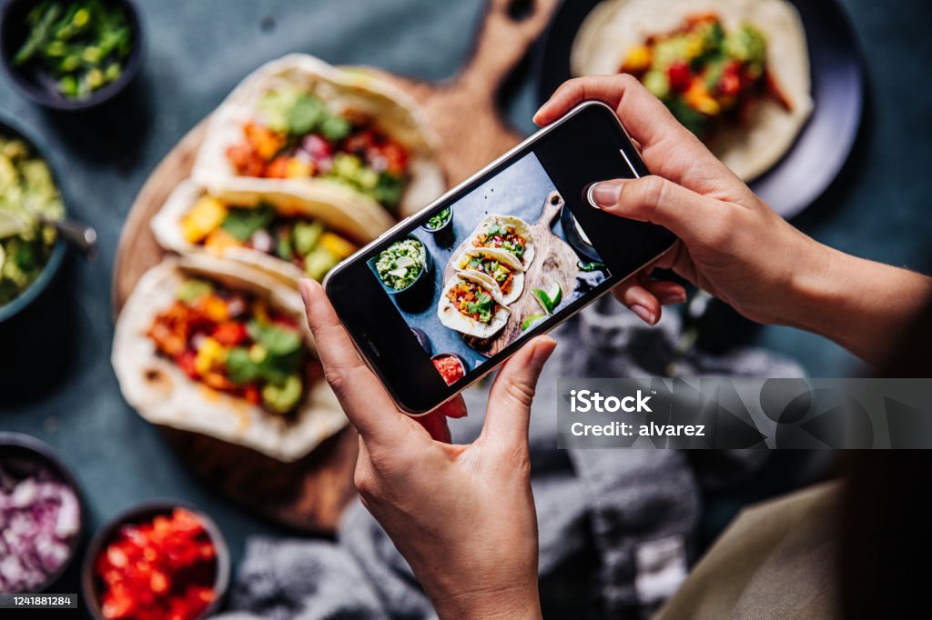 Hands of cook photographing Mexican tacos Hand of a chef taking photograph of tacos on table with a mobile phone. Hands of cook photographing Mexican food . Food Stock Photo