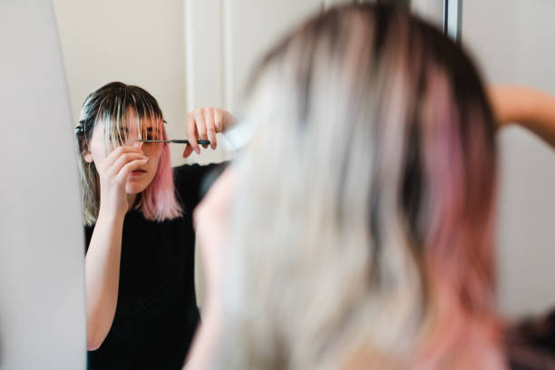 Young girl cutting her own hair during lock down Young girl cutting her own hair during lock down fringe stock pictures, royalty-free photos & images