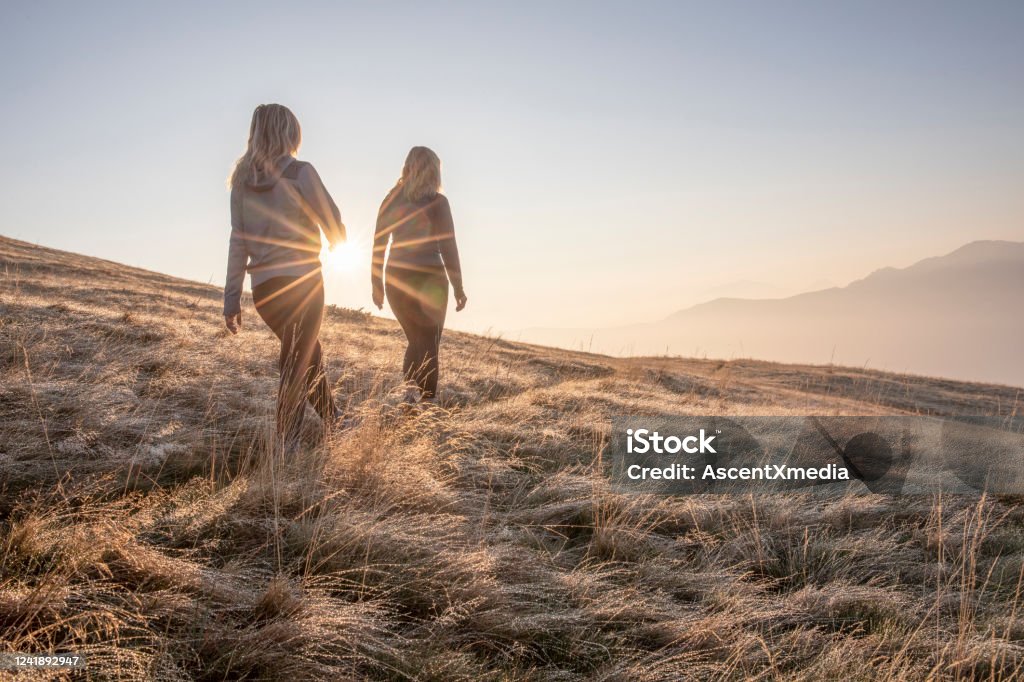 Wanderinnen wandern bei Sonnenaufgang auf der Graswiese - Lizenzfrei Natur Stock-Foto