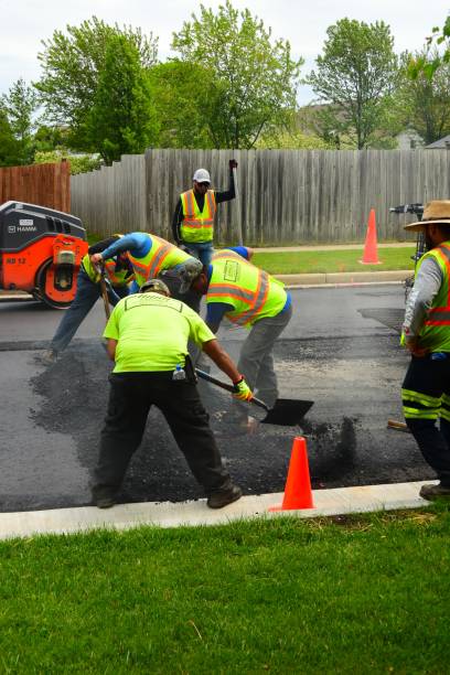 Teamwork filling in around a sewer cover during road repair Sturtevant, Wisconsin / USA - June 1, 2020: Asphalt crew works around a manhole cover manually to fill in where the large equipment is unable to  fill to the projecting sewer grid. hard bituminous coal stock pictures, royalty-free photos & images