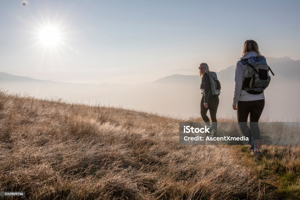 Wanderinnen wandern bei Sonnenaufgang auf der Graswiese - Lizenzfrei Wandern Stock-Foto Wanderinnen wandern bei Sonnenaufgang auf der Graswiese - Lizenzfrei Wandern Stock-Foto