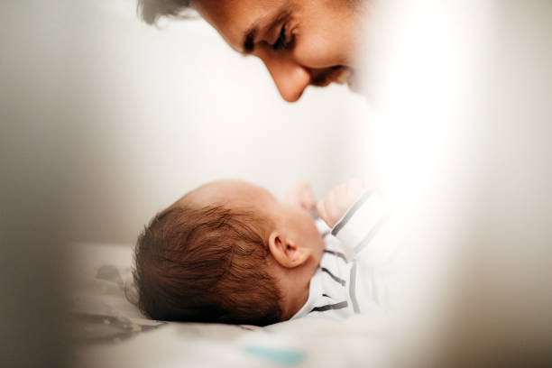 A newborn baby holding a boy's finger