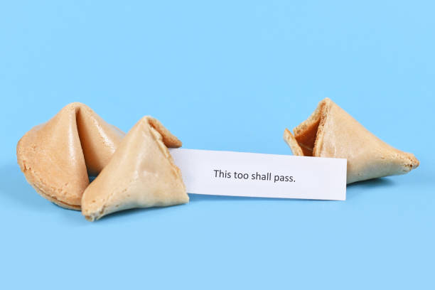 istock Broken up and whole fortune cookie with motivational text 'This too shall pass' on paper note on blue background 1241926216