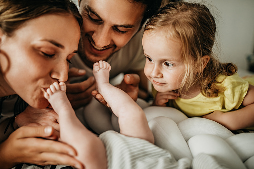 Family playing with new baby member in bed