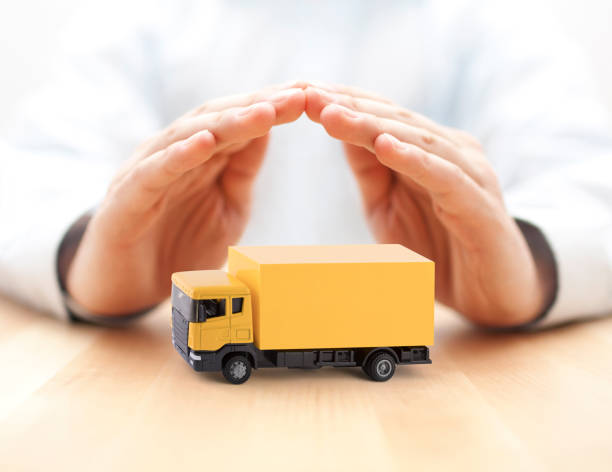 istock Yellow cargo delivery truck miniature protected by hands 1241928404
