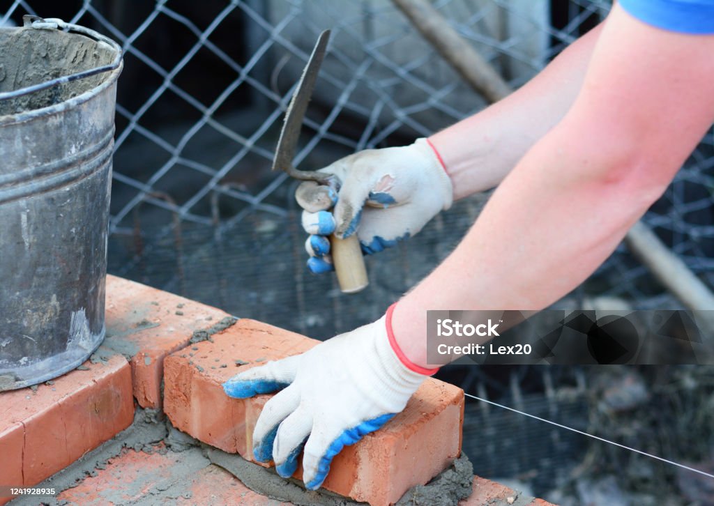 A Builder Is Laying Bricks With Cement And Trowel Using Masons