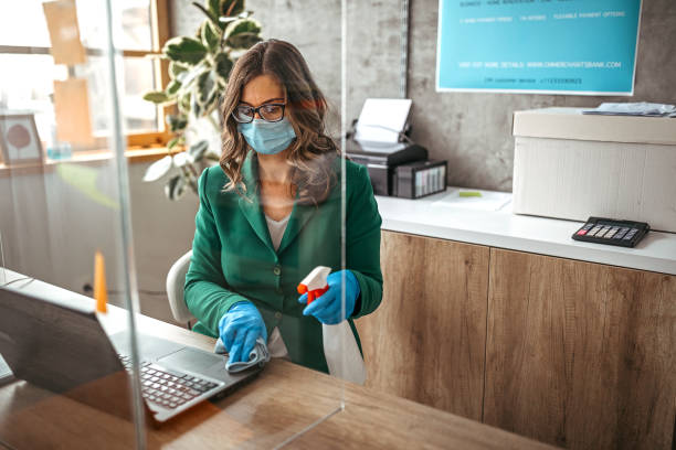 Disinfection before work Businesswoman with surgical gloves cleans and disinfects his table in the office. Office with acrylic glass partition on desk. Acrylic glass wall - protection against coughs and spitting, protection against viruses. splash screen stock pictures, royalty-free photos & images