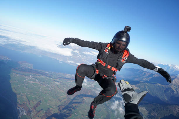 skydivers fall through clear skies, aerial flight - mountain drop europe switzerland imagens e fotografias de stock