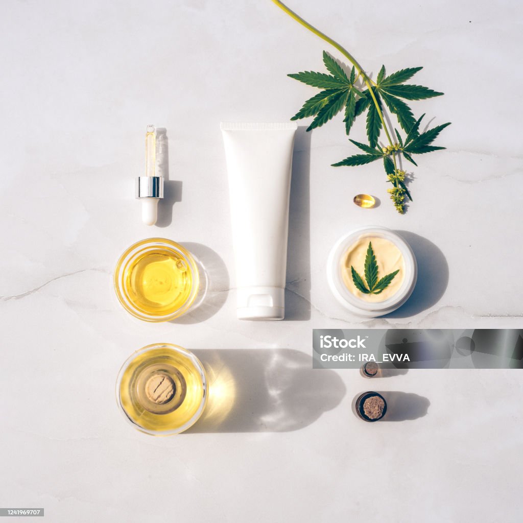 Cosmetics CBD oil. Cosmetic Products with cannabis Oil, tincture Flat lay Tuba and jar of cream CBD oil, THC tincture and hemp leaves on marble background. Flat lay, minimalism. Cosmetics CBD oil. Cream with hemp oil and marijuana leaves Cannabidiol Stock Photo
