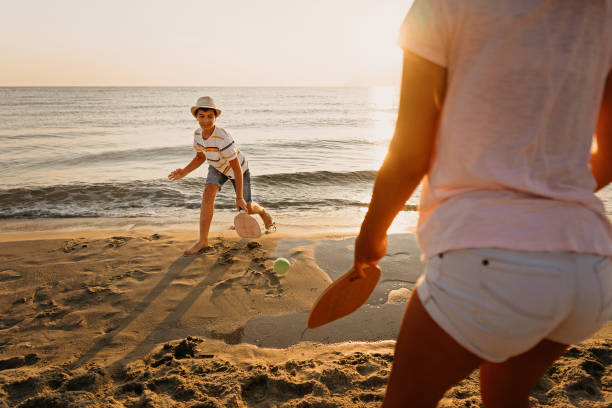 Teenage girl and boy playing beach tennis on sand