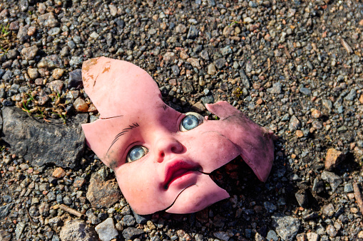 Old broken doll face on ground