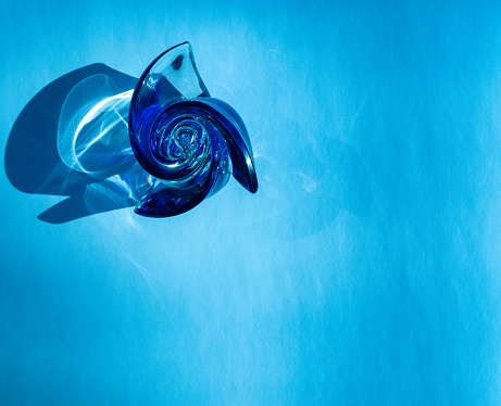 Beautiful Blue glass rose on an aqua background casting swirling shadows and bright reflections