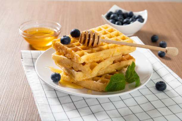 istock Delicious Belgian waffles on a plate with honey and fresh blueberries 1241996055