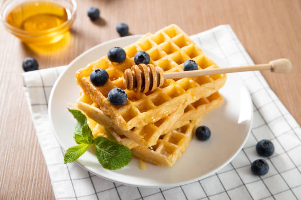 istock Delicious Belgian waffles on a plate with honey and fresh blueberries 1241999841