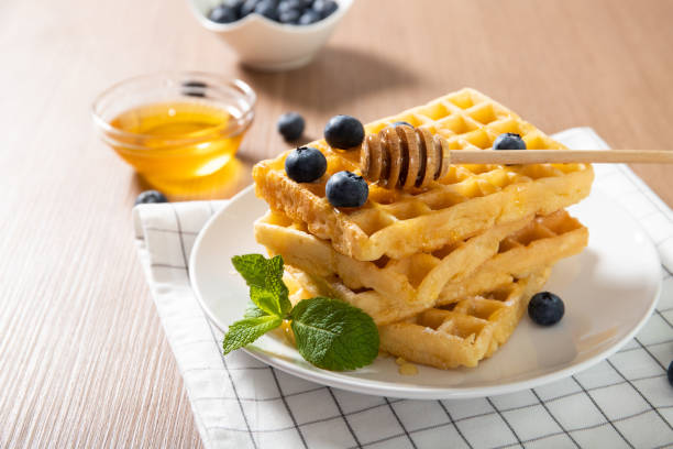 istock Delicious Belgian waffles on a plate with honey and fresh blueberries 1242000367