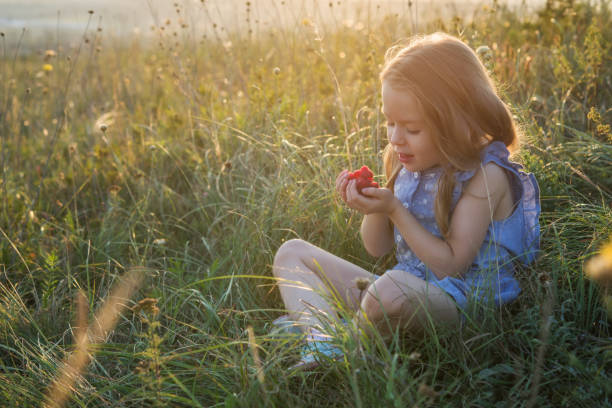 Little pretty girl with the raspberry on her fingers