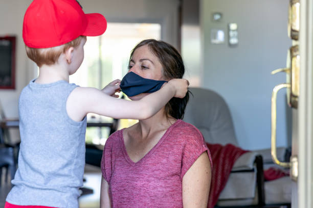 istock Cute Kid Putting Protective Face Mask on His Mother 1242029625