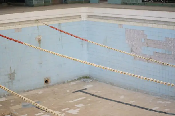 Photo of Detail of abandoned imperial times swimming bath, light blue tiled deep pool with separating floating leads