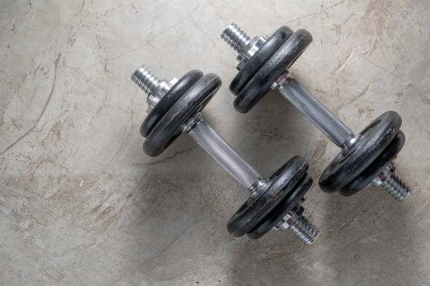 istock Dumbbells for muscle building exercise placed on cement floor with copyspace.Body workout in the gym training concept.new normal popular lifestyles for strong and healthy bodybuilding at home 1242055969