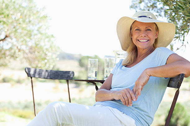 portret szczęśliwy dojrzała kobieta siedzi w fotel - kapelusz słoneczny zdjęcia i obrazy z banku zdjęć