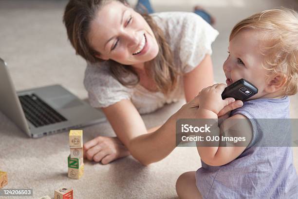 Mujer Sonriente Trabajando En Portátil Y Bebé Jugando Foto de stock y más banco de imágenes de 12-17 meses