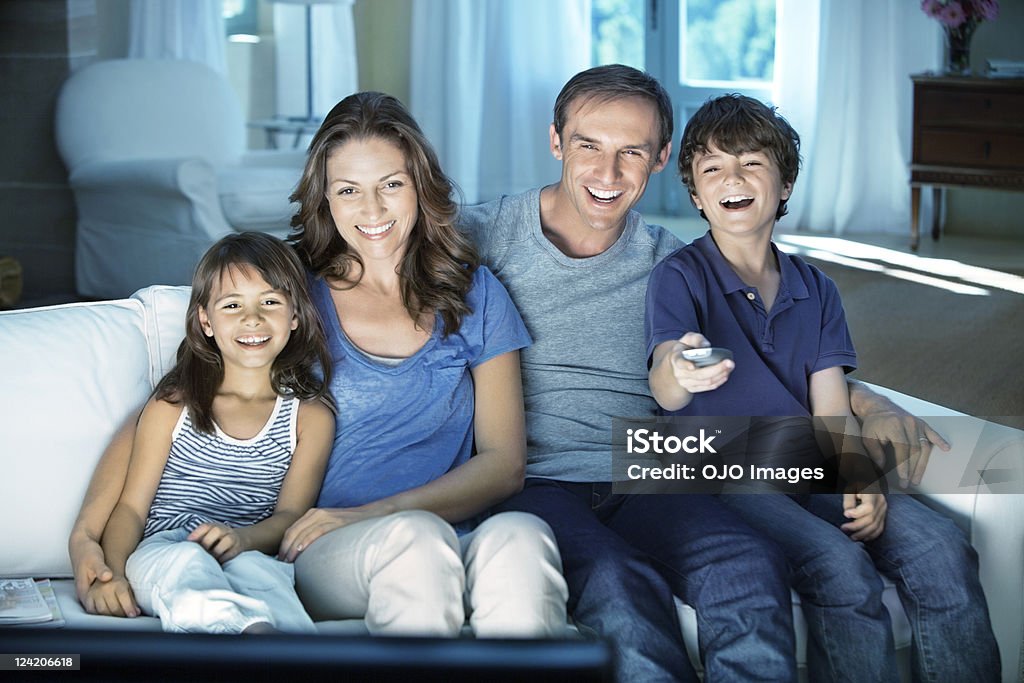 Счастливая пара с двумя детьми, наслаждаясь телевизор у себя дома - Стоковые фото Смотреть телевизор роялти-фри