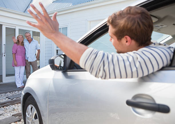 hombre joven en el coche agitando adiós a la habitación de sus padres - car for sale fotografías e imágenes de stock