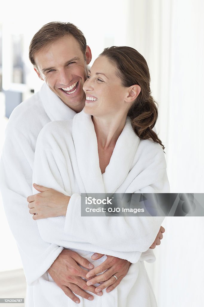 Heureux couple d'âge moyen embrassant dans un peignoir - Photo de Peignoir libre de droits