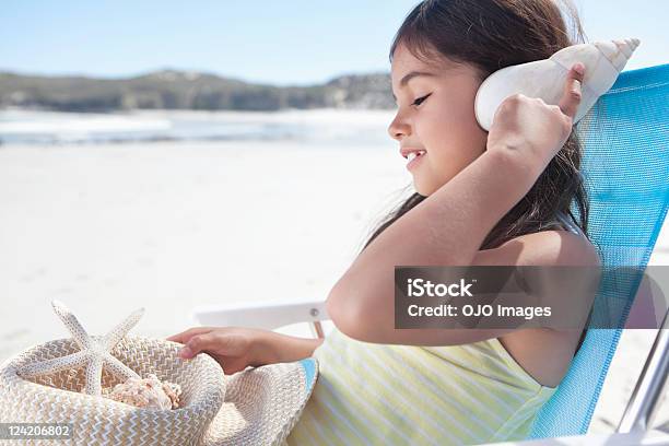 Linda Niña Escucha Carcasa Con Vista Al Mar Foto de stock y más banco de imágenes de Concha - Parte del cuerpo animal - Concha - Parte del cuerpo animal, Escuchar, Niño