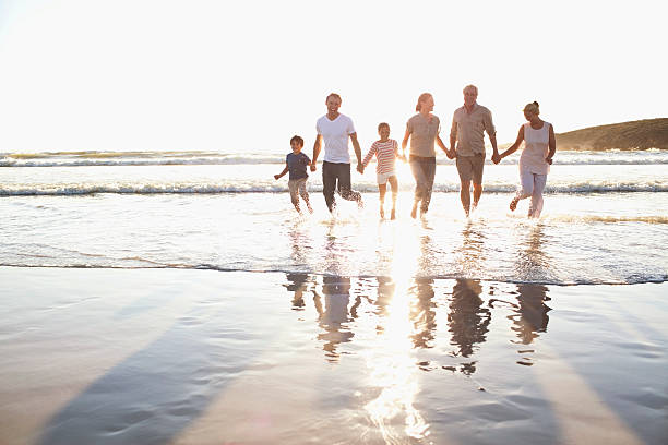 familia sosteniendo las manos en el agua en la playa - family beach vacations travel fotografías e imágenes de stock