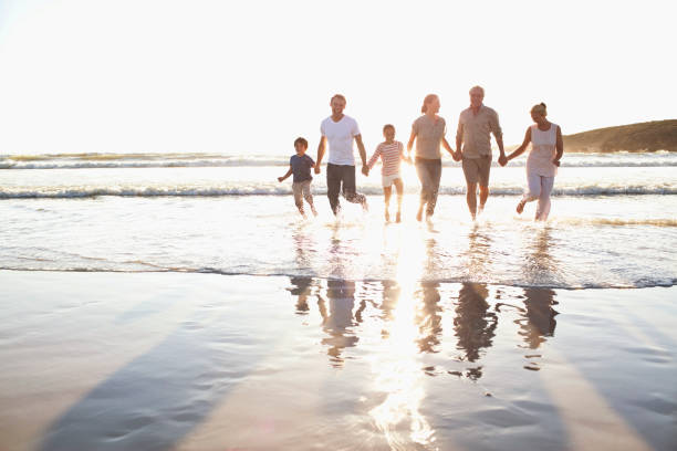 Family holding hands in water at beach  mid distance stock pictures, royalty-free photos & images