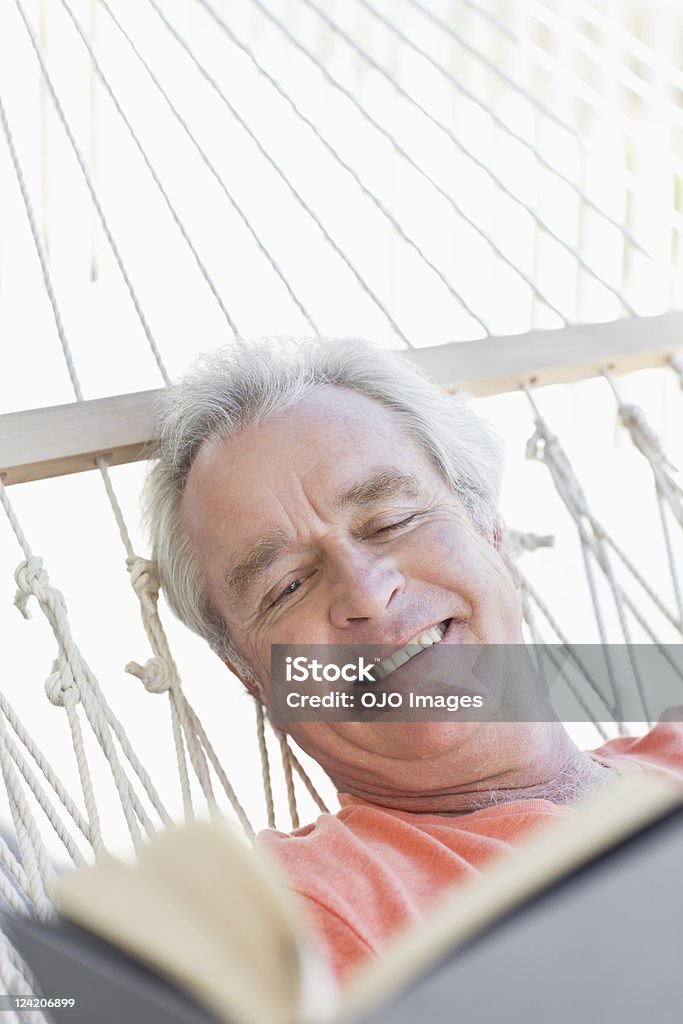 Close-up of happy senior man reading book in hammock  60-64 Years Stock Photo
