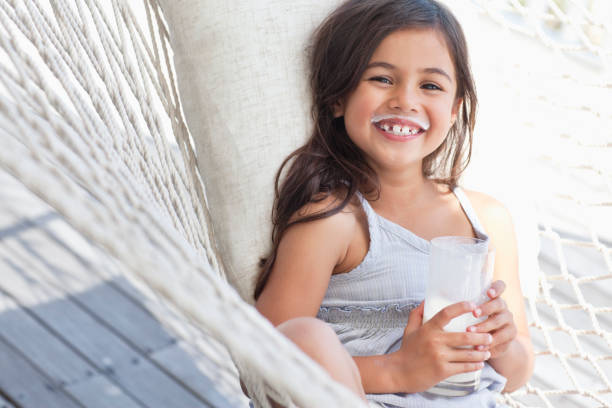 portrait d'une joyeuse jolie fille souriante tenant un verre de lait - milk child drinking little girls photos et images de collection