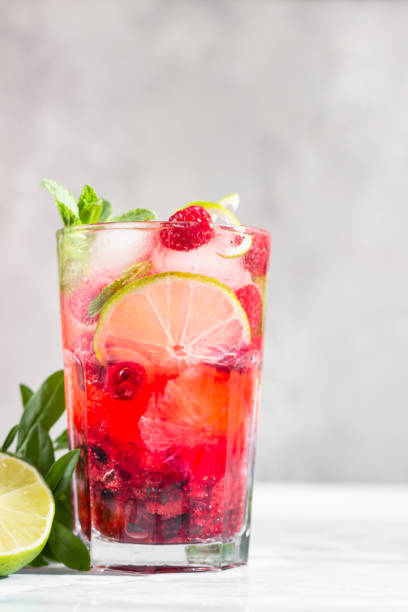 istock Lemonade or non-alcohol cocktail with raspberry, lime and mint in glass on grey stone background. Summer berry drink. 1242071553