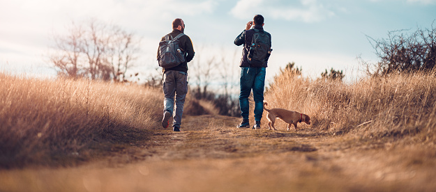 Friends with a small yellow dog walk the village path and observe nature through the binoculars.