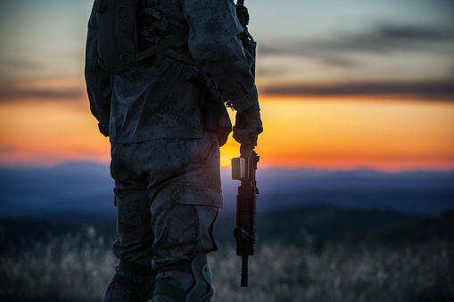 rifle in the soldier's hand at sunset