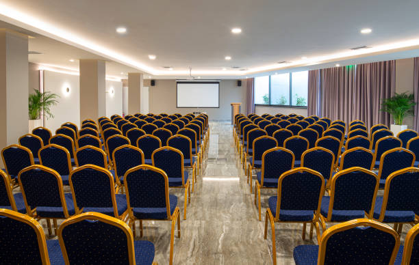 istock Front view of luxury auditorium interior with empty white screen. Modern conference hall with rows of vintage blue and golden chairs 1242127036