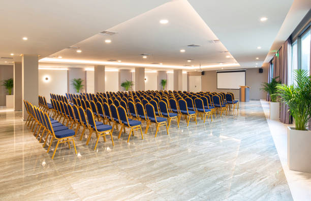 istock Side view of luxury auditorium interior with empty white screen and vintage blue seats. Modern conference hall background with copy space 1242127038