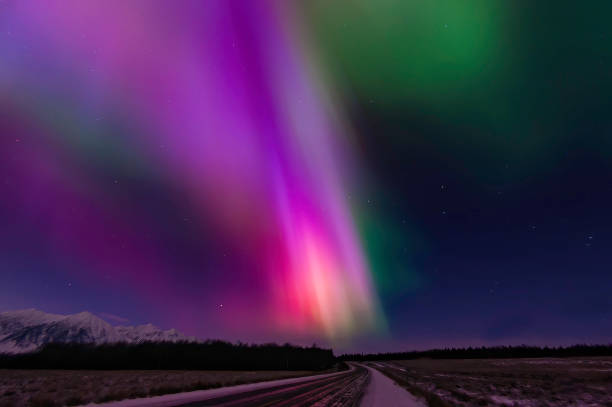 The aurora borealis is a natural light display in the sky particularly in the high latitude of the Arctic regions, caused by the collision of energetic charged particles with atoms in the high altitude atmosphere (thermosphere). Major solar flare causing The aurora borealis is a natural light display in the sky particularly in the high latitude of the Arctic regions, caused by the collision of energetic charged particles with atoms in the high altitude atmosphere (thermosphere). Major solar flare causing great Aurora borealis over Kluane National Park, Yukon, Canada. Coronas form of aurora. aurora borealis orange stock pictures, royalty-free photos & images