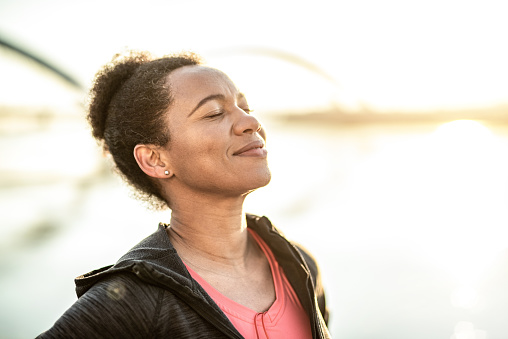 Sporty African American woman enjoying sunlight and day dreaming.