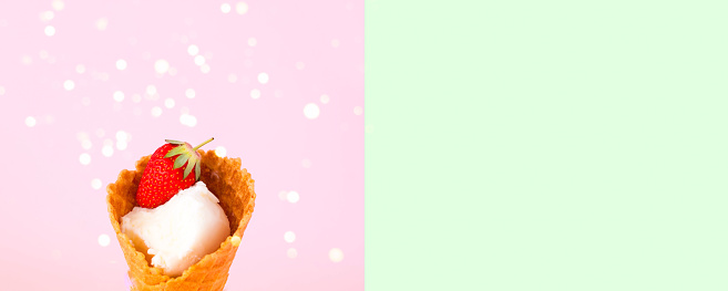 Ice cream in waffle cone with fresh strawberries on pink background. National ice cream day 19 july concept. Close-up, creative copy space.