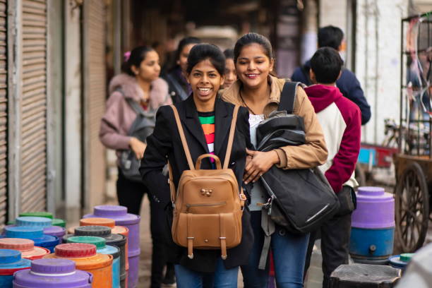 Young women carry backpacks on a chest at a street of Old Delhi, India. stock photo